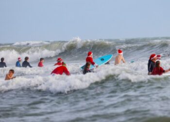 En tablas de surf, Papás Noel toman playa en Florida por diversión y una buena causa (FOTOS)